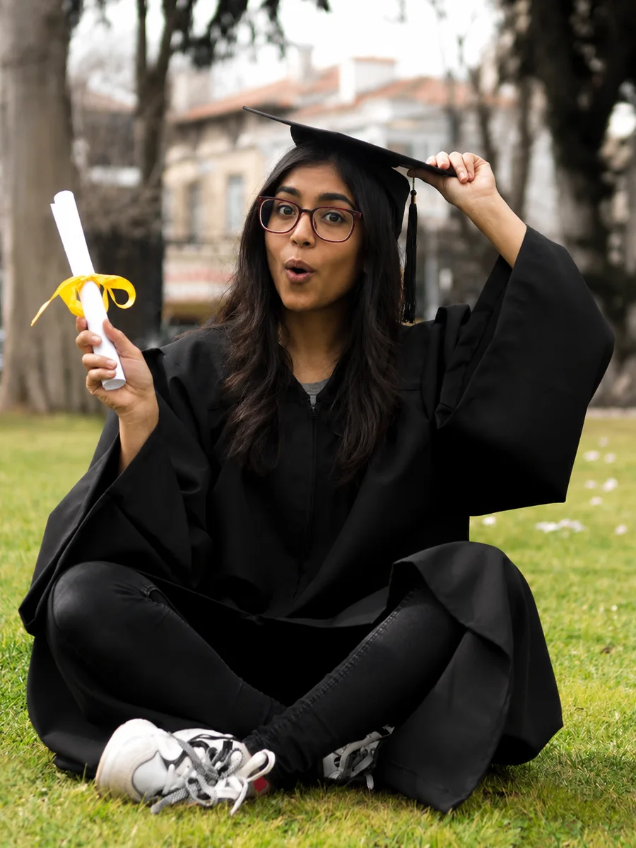 An Indian graduate in cap and gown holding her certificate
