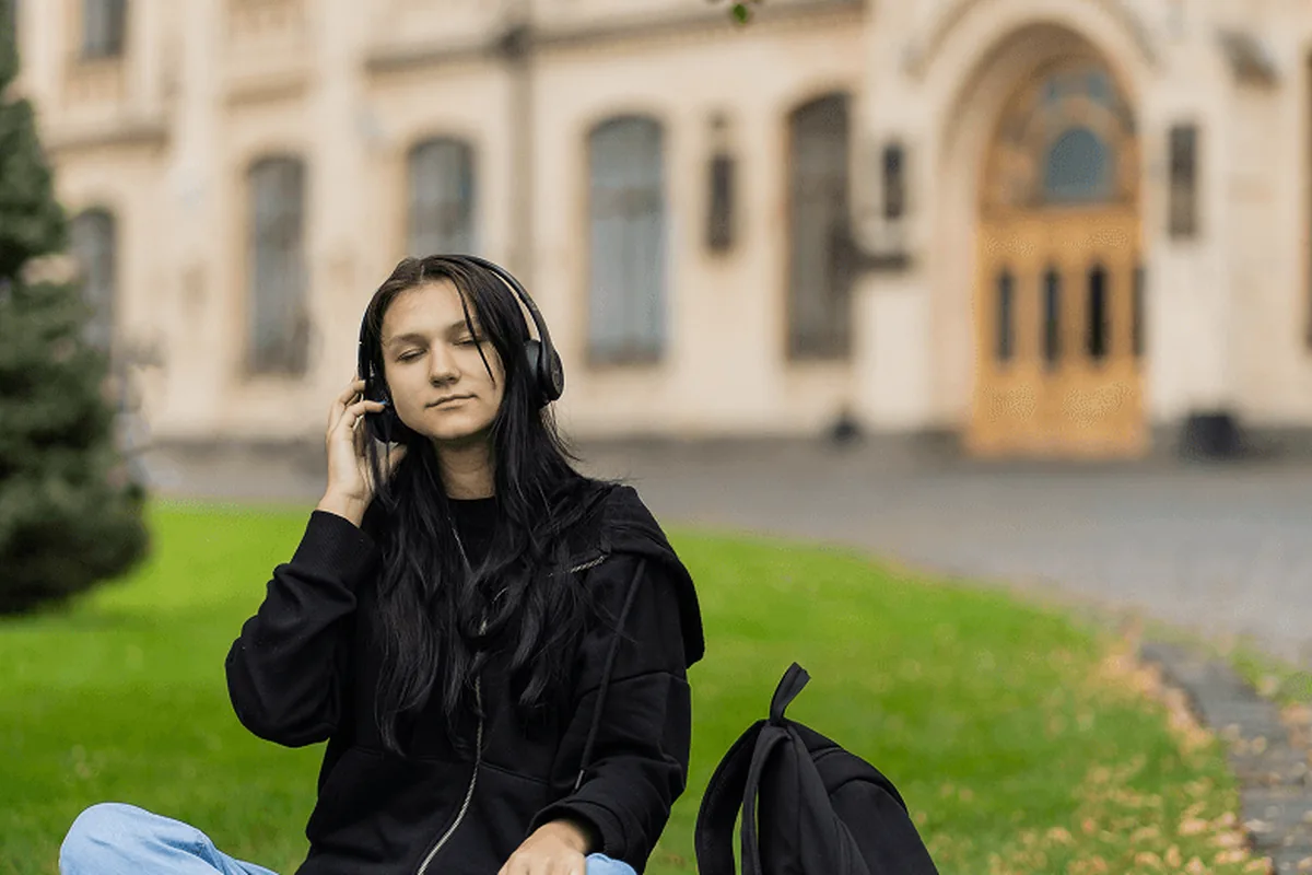 A student sitting on the lawn outside a university
